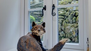 A fox sculpture on a window sill with a view of a rocky garden. - 2 Bed in Lynmouth (oc-foxcot) (Lynmouth)