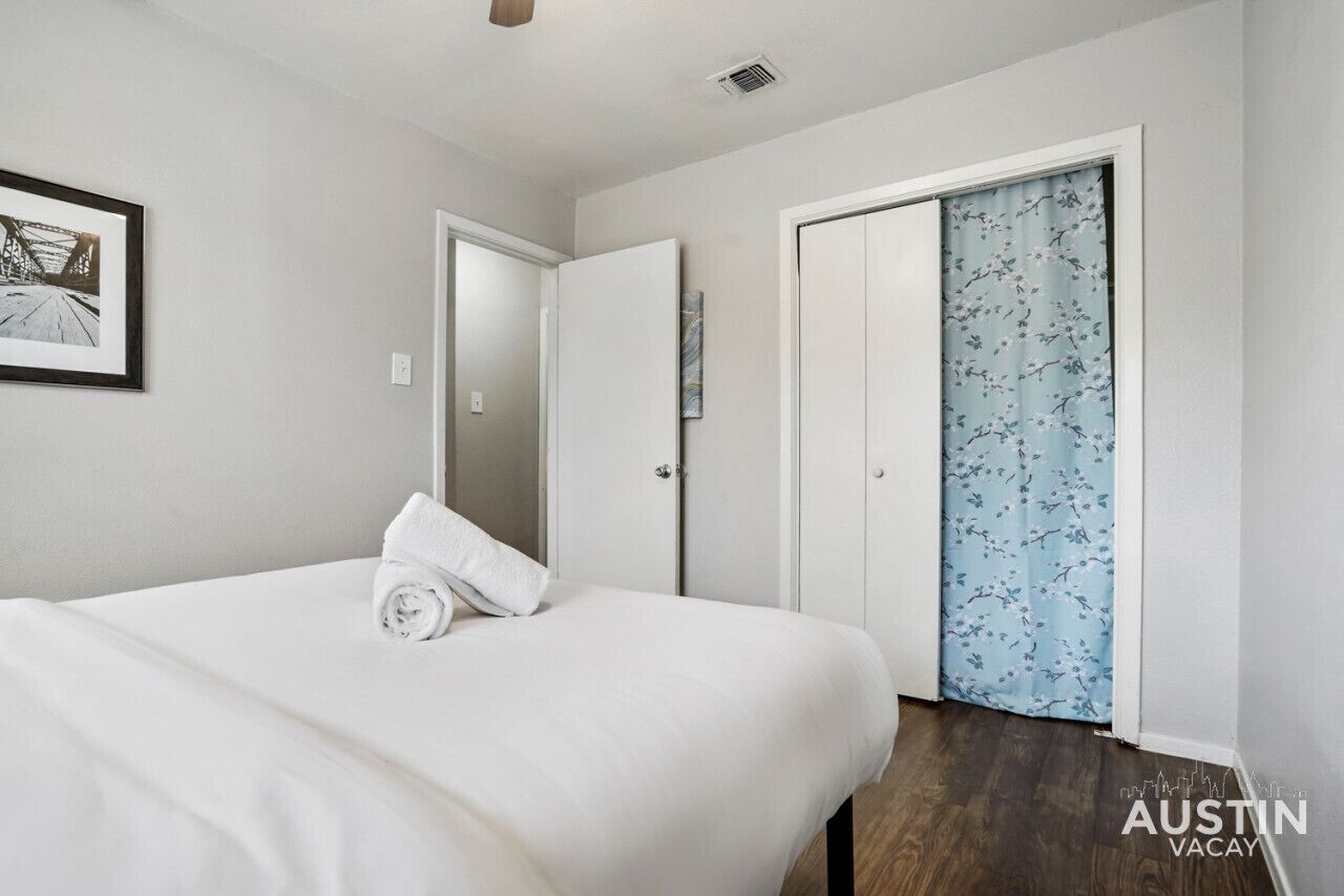 A hotel room with a bed, a door, and a window with a floral curtain.