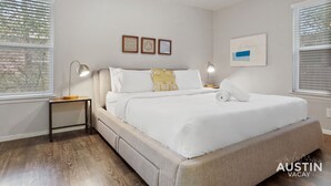 A bedroom with a bed, bedside tables, and artwork on the walls. - Kinney #4 xxxxxxxxxx (Austin)