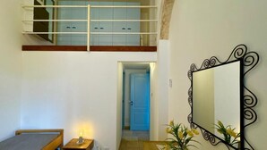 Une pièce comprenant un lit, une table de chevet avec une lampe, un miroir et un escalier menant à un étage supérieur.