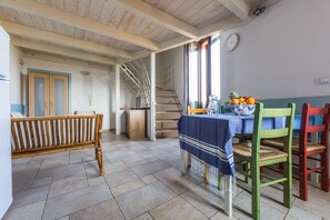 A dining area with a table set for two, a staircase, and a wardrobe. - A step away from the sea - Apartment A / SELENE (Monopoli)