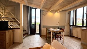 Un vaste espace de vie agrémenté d’un escalier en bois, d’une table à manger avec des chaises et de grandes fenêtres offrant une vue sur l’extérieur.