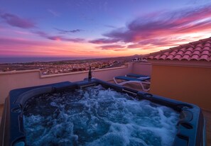 A hot tub with a city view at sunset.