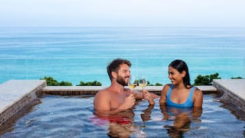 A couple in a hot tub with a view of the ocean.