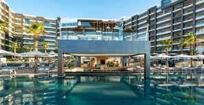 Ein modernes Hotel mit Dachterrasse, Pool und mehreren Balkonen.