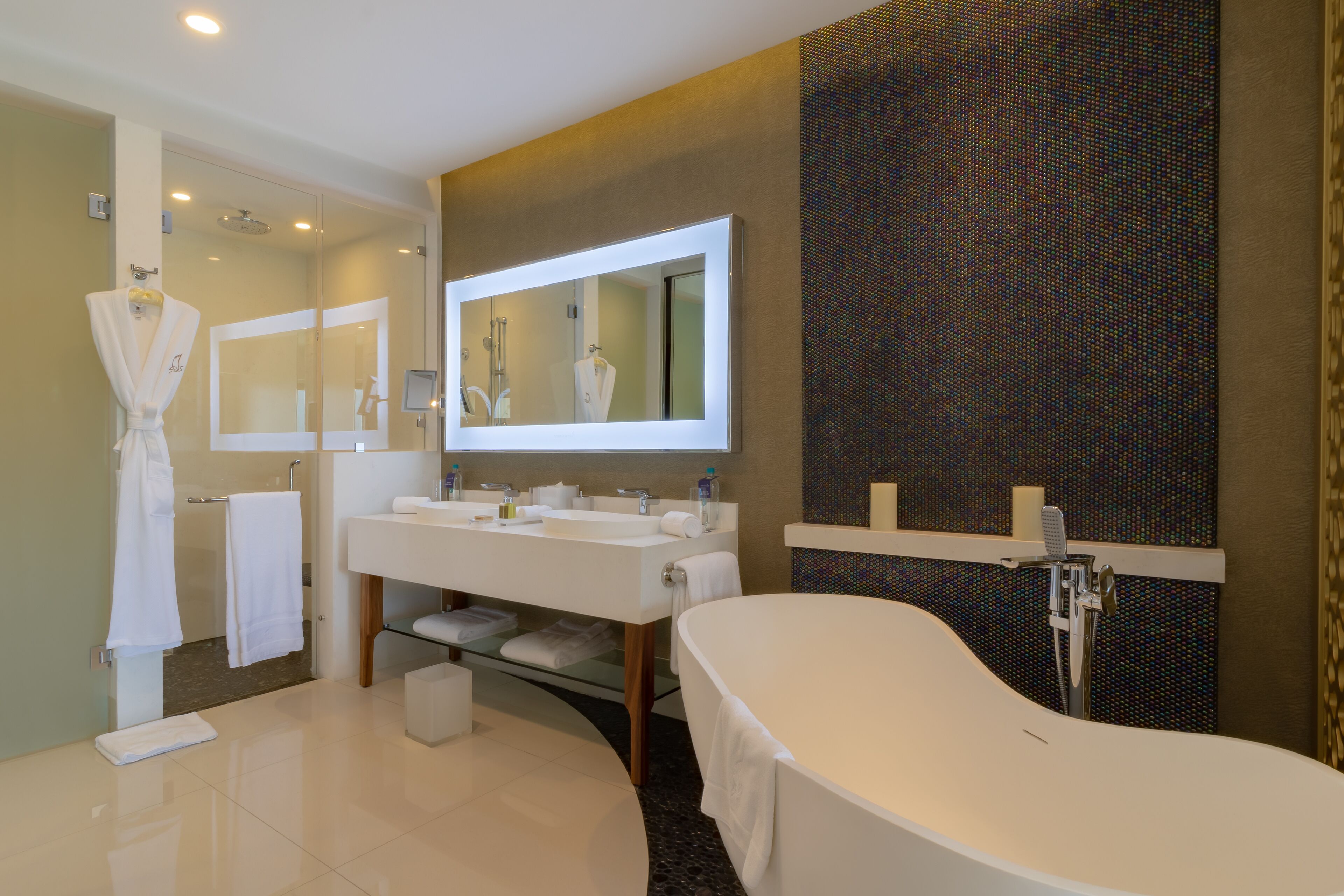 A modern bathroom with a large mirror, a bathtub, and a vanity with two sinks.