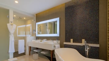 A modern bathroom with a large mirror, a bathtub, and a vanity with two sinks.