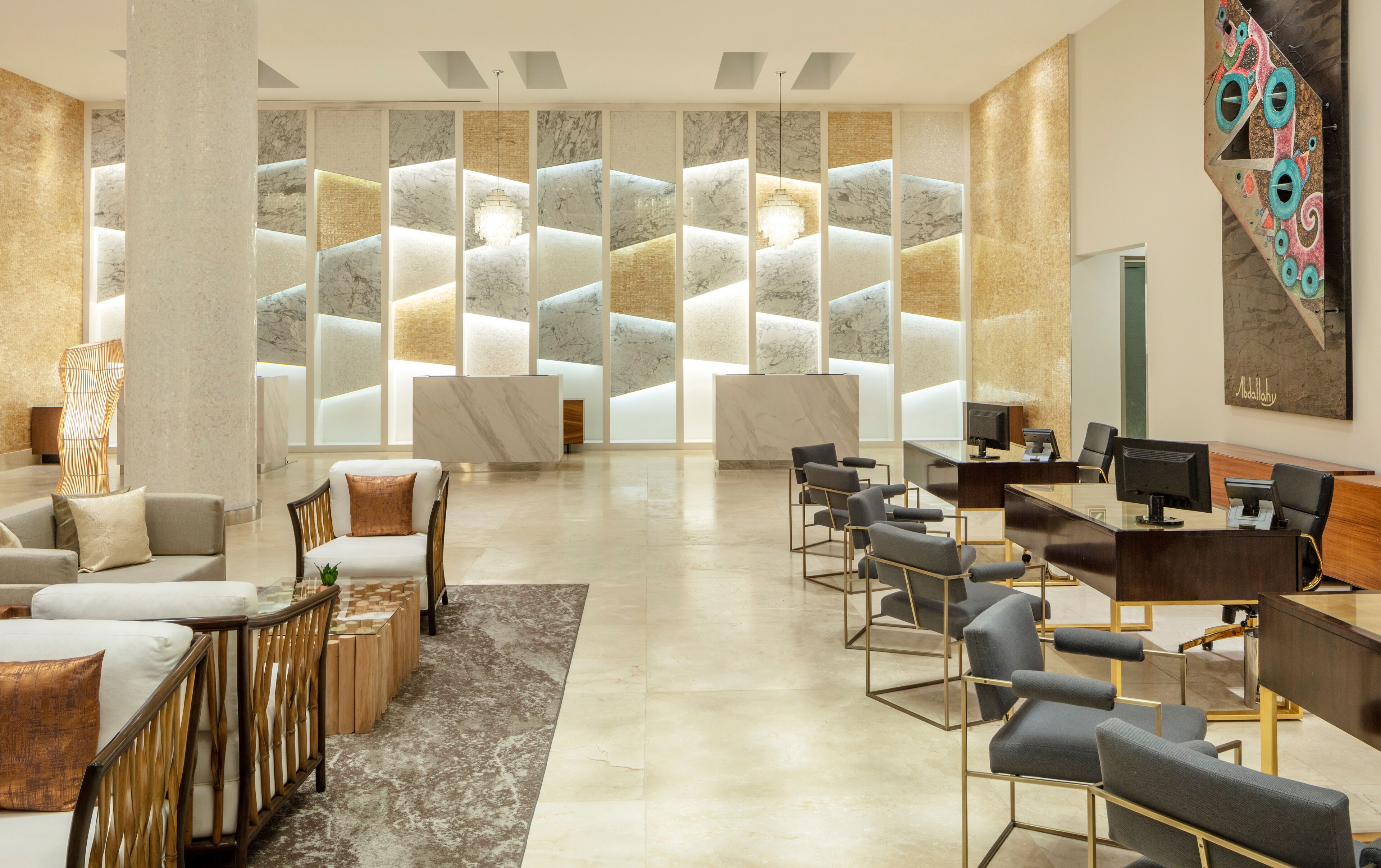 A modern reception area with a marble reception desk, multiple seating options including sofas and chairs, and a large abstract painting on the wall.