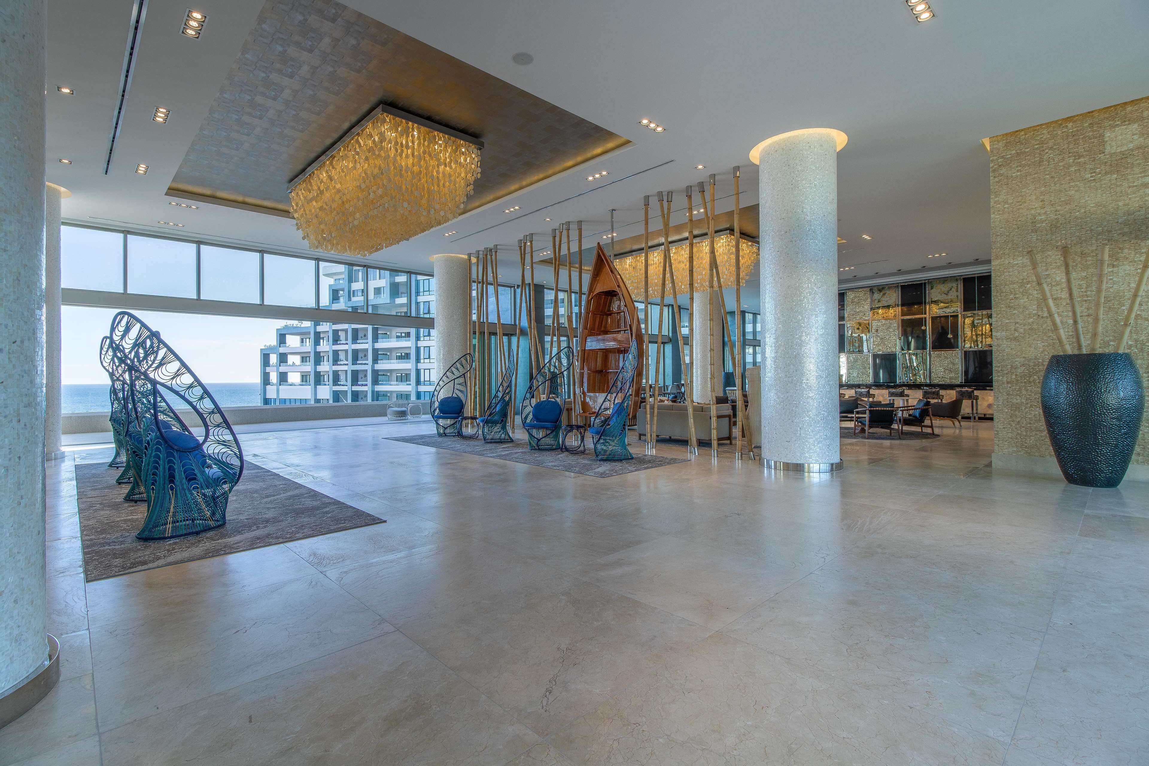 A spacious lobby with high ceilings, a large chandelier, and modern seating arrangements.