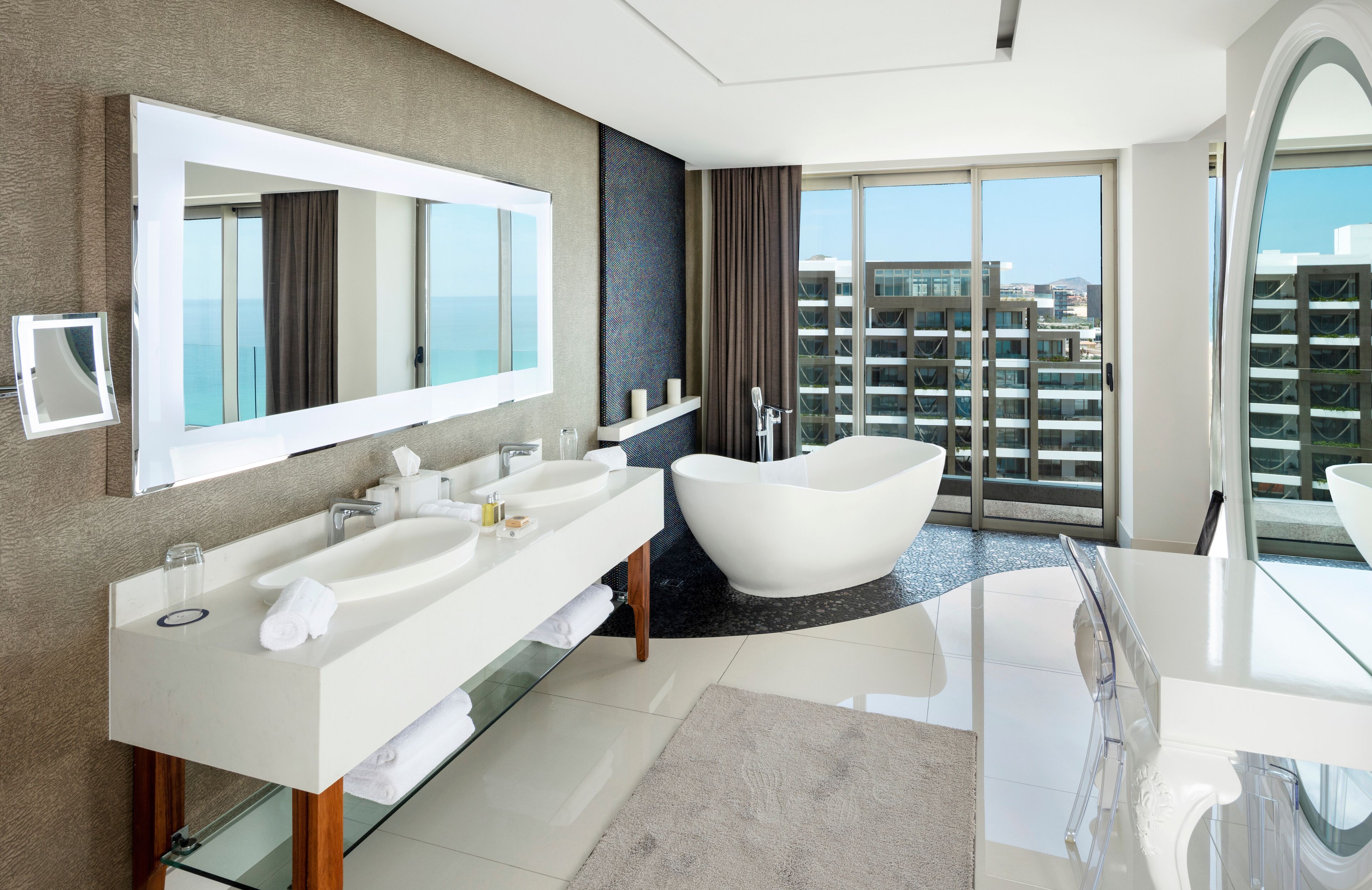 A modern bathroom with a large mirror, two sinks, a bathtub, and a glass shower enclosure.