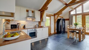 A kitchen with white cabinets, a built-in oven, a microwave, and a dining area with a table and chairs. - 2 Bed in Landkey (oc-cartl) (Landkey)