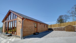 A wooden cabin with large windows, a sloped roof, and a gravel driveway. - 2 Bed in Landkey (oc-cartl) (Landkey)