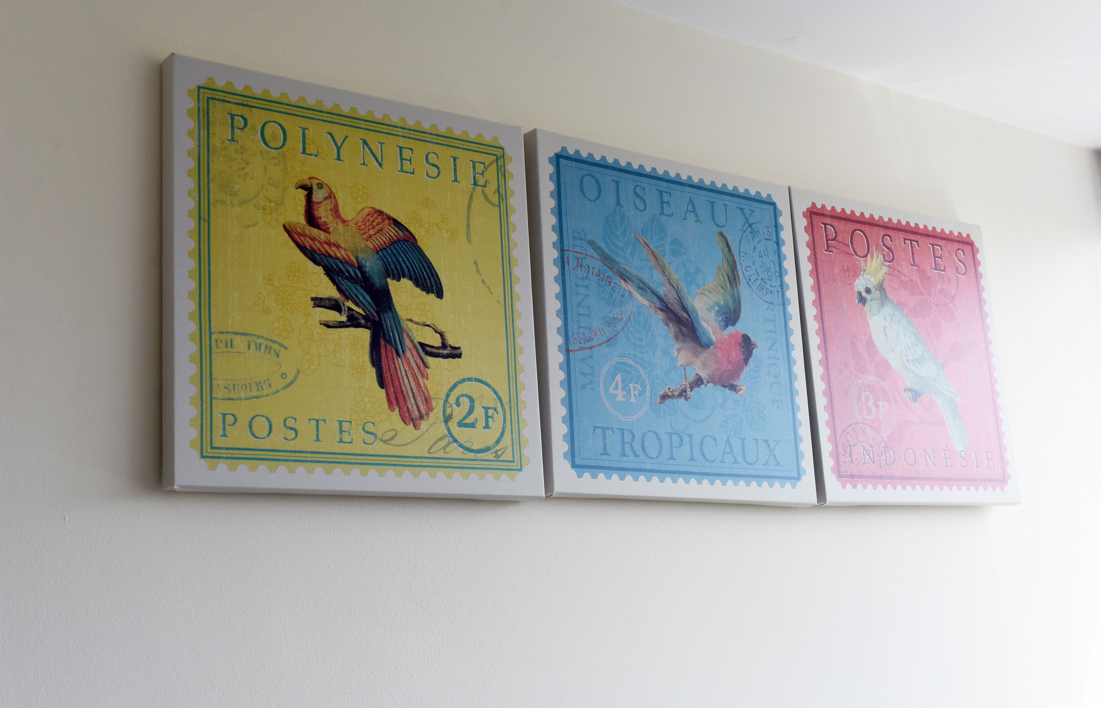 Drei Briefmarken an einer Wand.