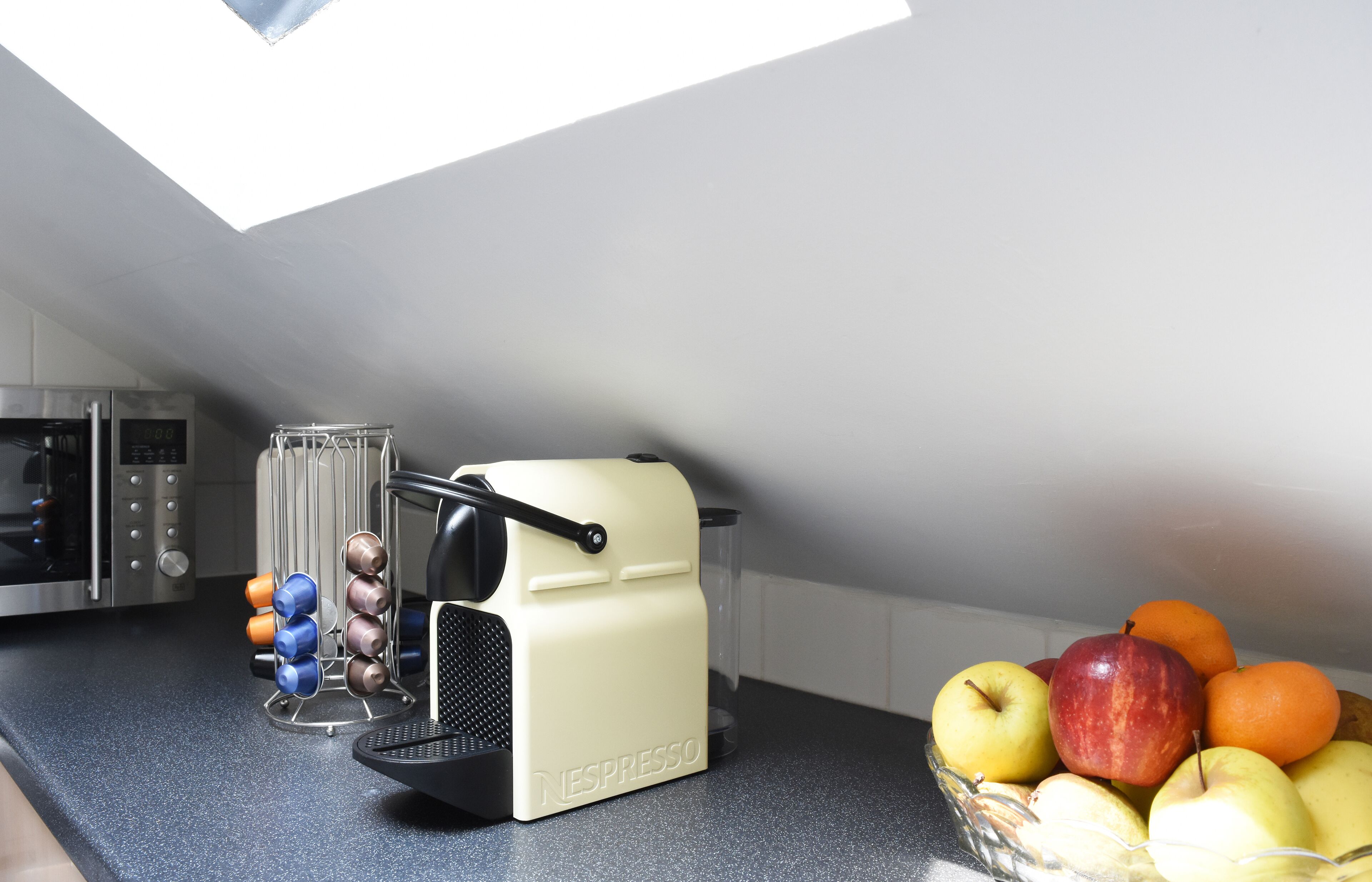 A kitchen with a Nespresso coffee machine, a fruit bowl, and a wine rack.