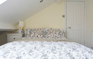 A bedroom with a bed, a nightstand, a lamp, and a door. - Stylish, comfortable apartment in  Leamington Spa (Royal Leamington Spa)