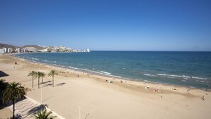 A wide beach with palm trees, a clear blue sky, and a calm sea. - Singular Stays Cullera Beach (Cullera)
