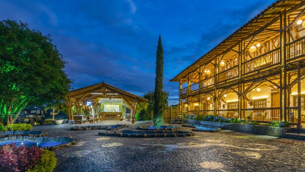 Un bâtiment traditionnel en bois, doté d’une cour en pierre, d’un kiosque en bois et d’un grand arbre.