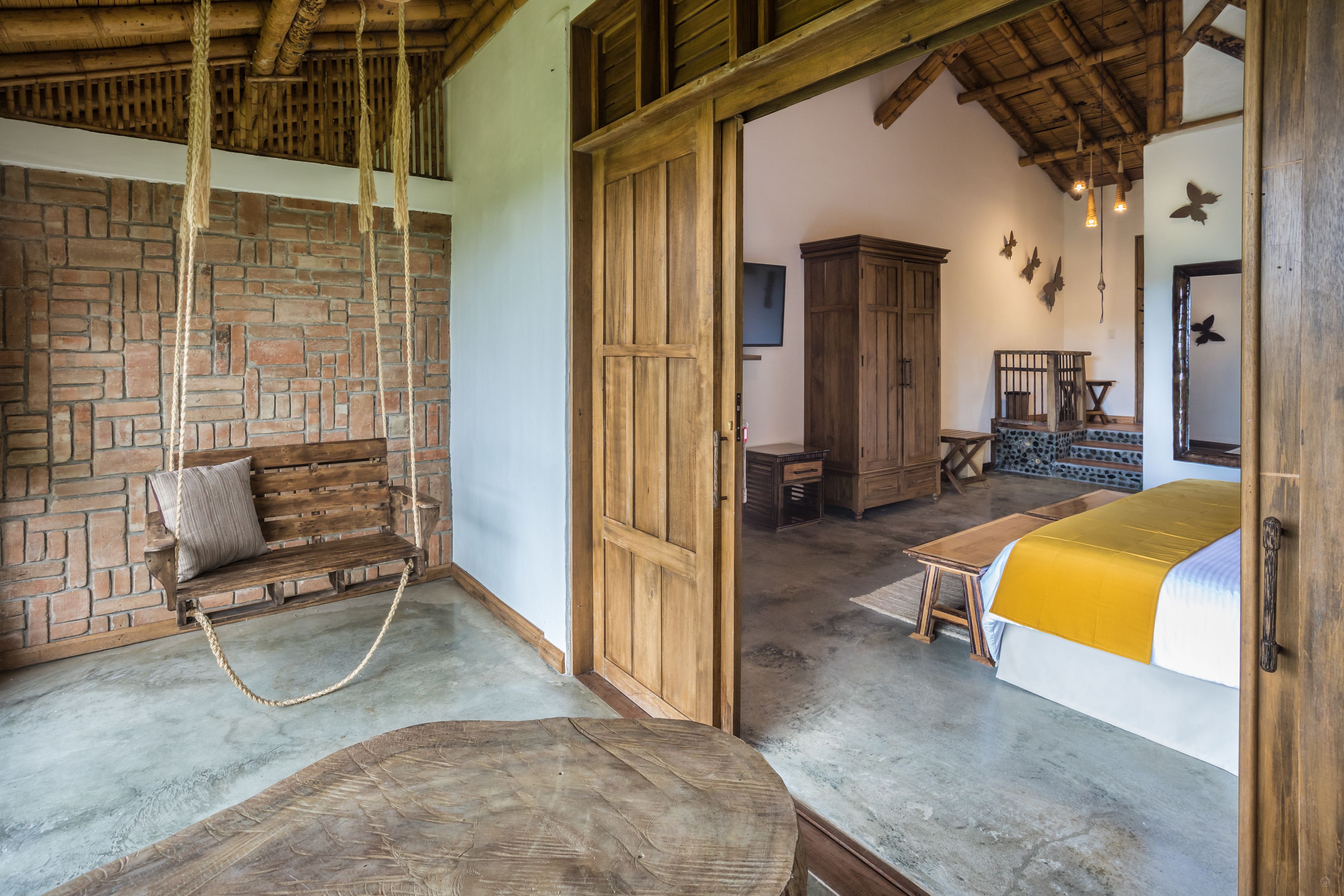 A rustic bedroom with a wooden bed, a bench, and a hanging rope swing.