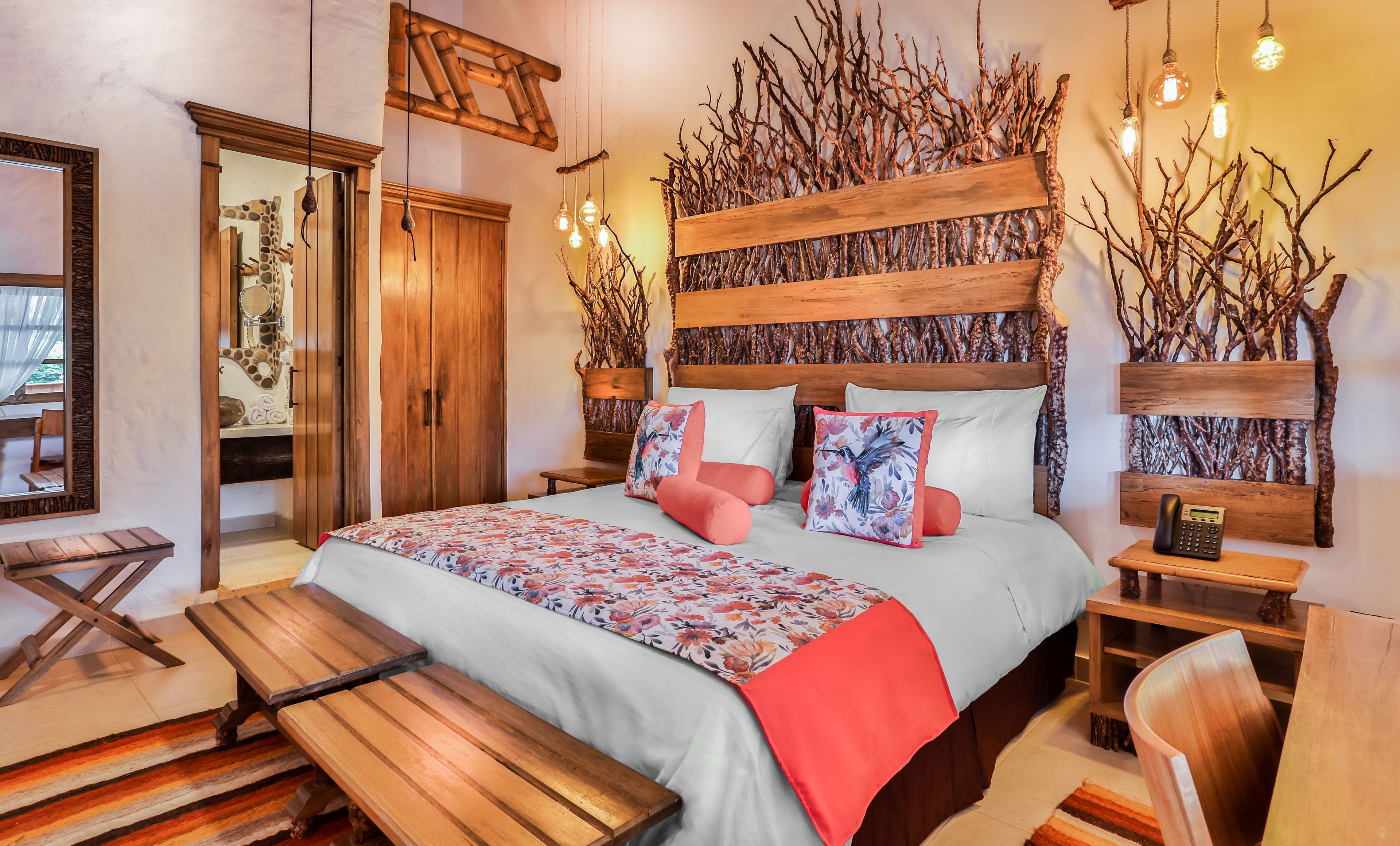 A bedroom with a large bed, wooden headboard, bedside tables, a bench, and a mirror.