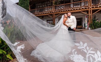 A wedding couple in front of a traditional building with a wooden balcony.
