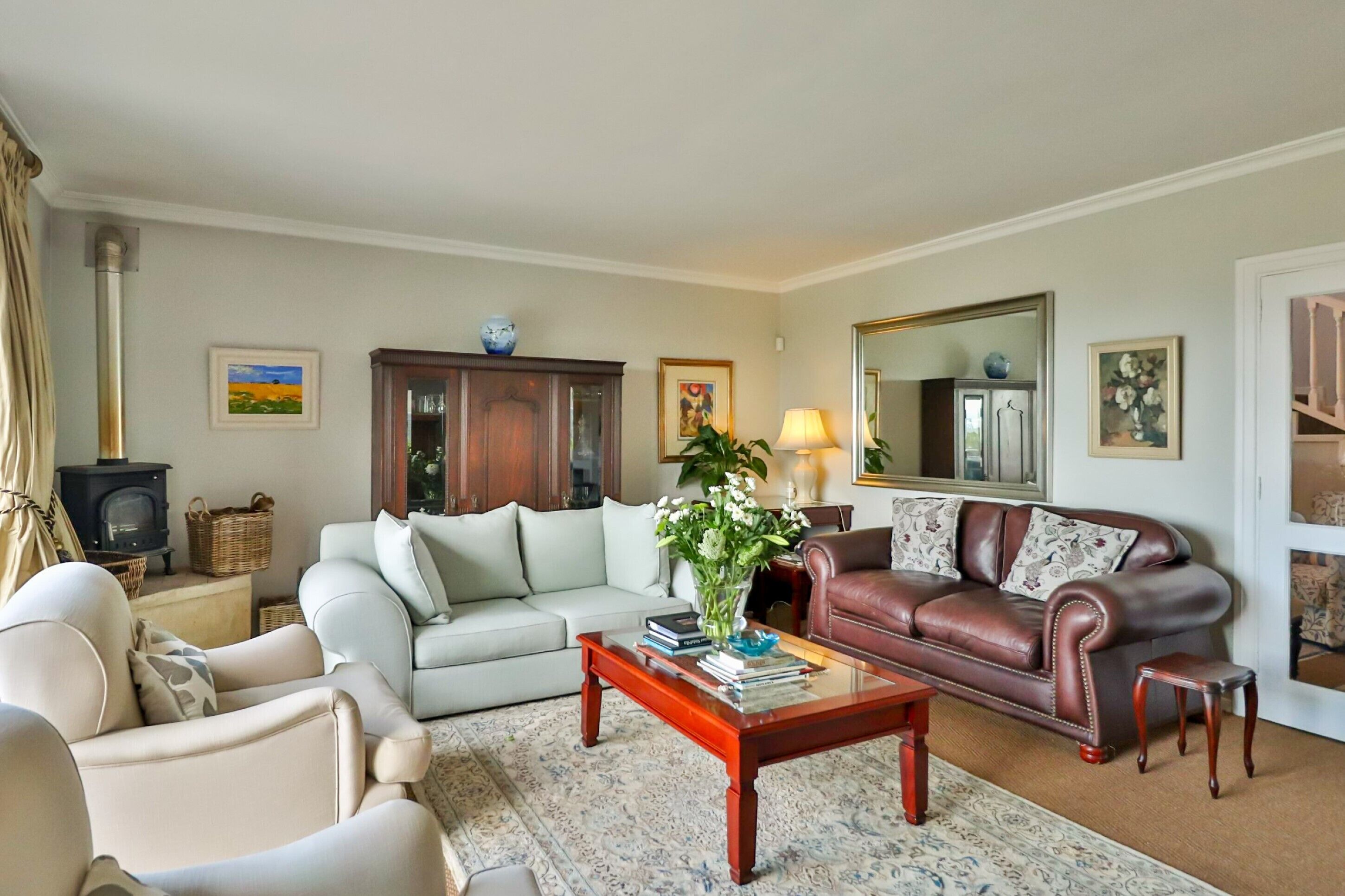 A living room with a sofa, armchair, and a coffee table with books and a vase.