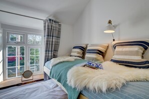 Un dormitorio con cama, ventana, lámpara y vistas al exterior.