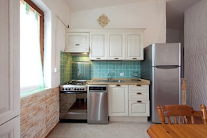 A compact kitchen with white cabinets, a stainless steel refrigerator, a dishwasher, and a stove.