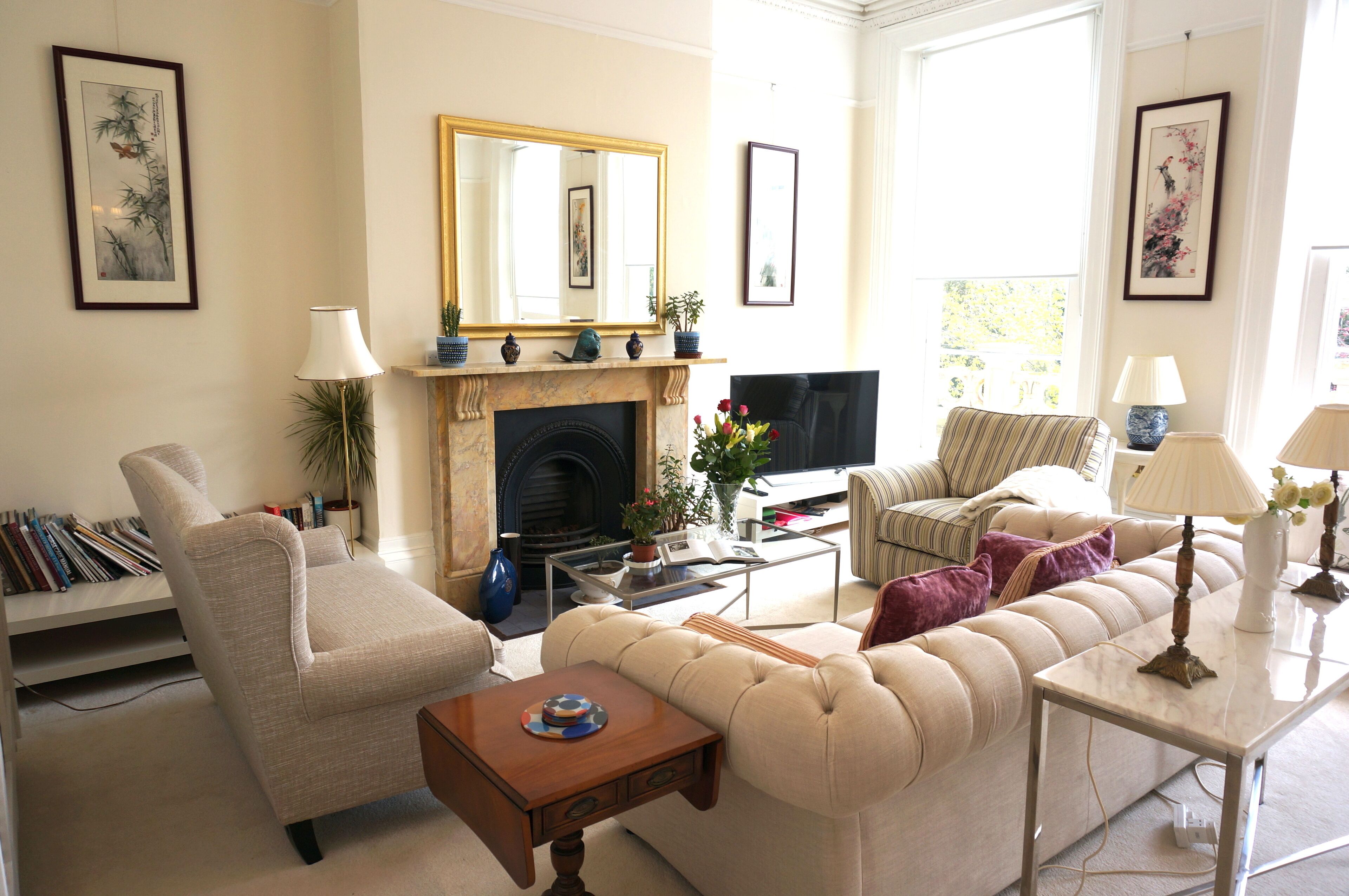 A living room with a fireplace, sofa, armchair, and a television.