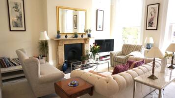 A living room with a fireplace, sofa, armchair, and a television.