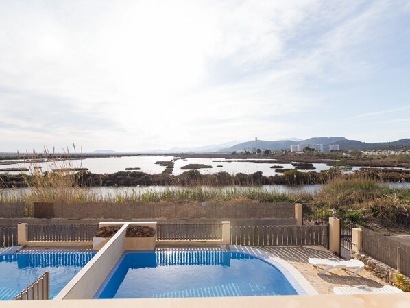 A swimming pool with a view of a natural landscape including water bodies and distant mountains.