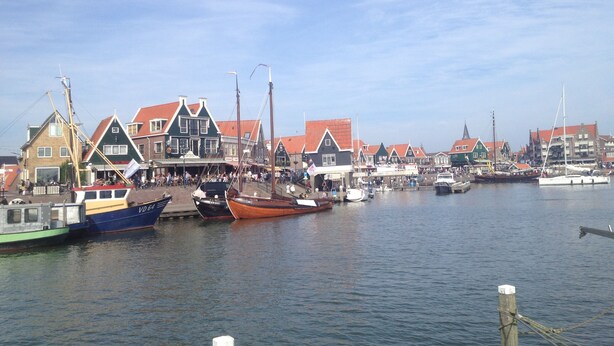 A harbor with boats docked and buildings with red roofs.