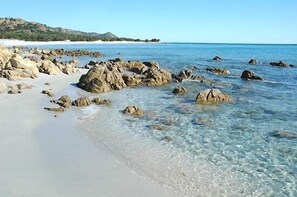 Una playa con aguas claras y poco profundas, y grandes rocas.