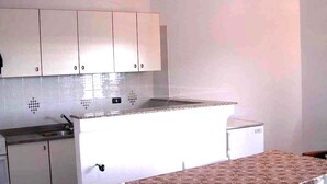 A kitchen with white cabinets, a countertop, and a small refrigerator.