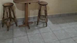 A room with a wooden table and two stools, a mirror on the wall, and tiled flooring. - Hotel Villa Aurora (Ezequiel Montes)