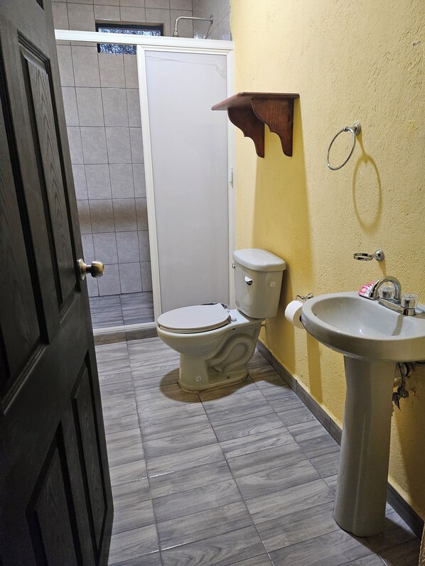 Un baño con inodoro, lavabo y ducha.