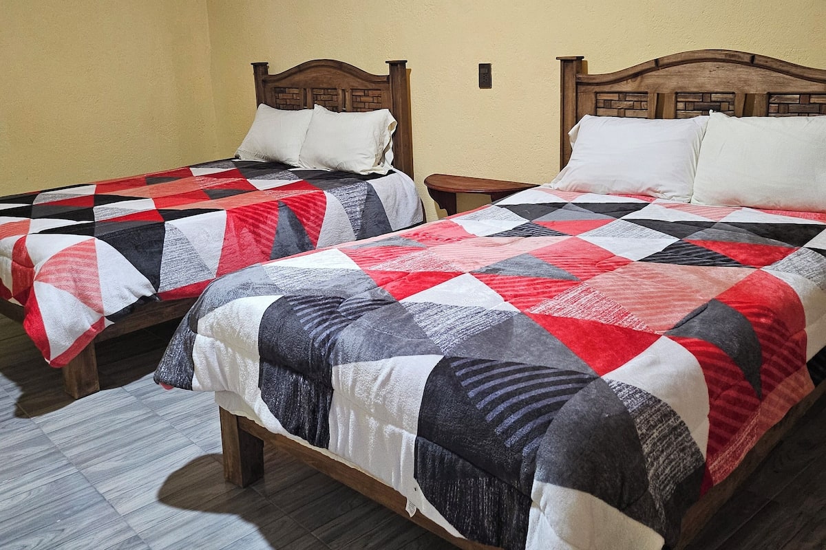 Two single beds with wooden headboards in a room with yellow walls and a tiled floor.