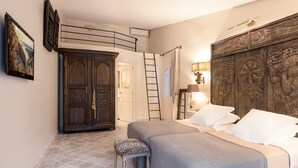 A bedroom with two beds, a wardrobe, a ladder, and a large decorative headboard. - Provencal villa in unique natural and calm setting with beautiful views (Fayence)