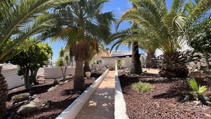 A pathway lined with palm trees and a white border, leading to a building with a tiled roof. - .."Beautiful luxury spacious 4 bed villa Costa Adeje with a heating pool".. (COSTA ADEJE)