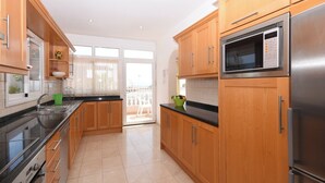 A modern kitchen with wooden cabinets, stainless steel appliances, and a large window. - .."Beautiful luxury spacious 4 bed villa Costa Adeje with a heating pool".. (COSTA ADEJE)