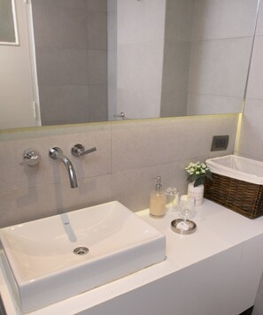 A bathroom with a white sink, a mirror, and a shower area.