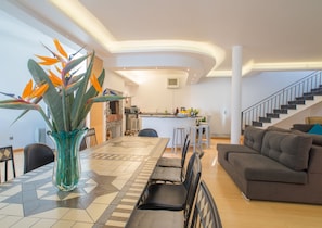 Ein modernes Wohnzimmer mit Essbereich, Küche und Treppe.
