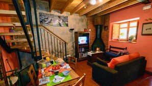 A cozy living room with a fireplace, a dining area with breakfast items, and a staircase leading to an upper level. - Tranquil Stay Near Luna River (Benllera, Carrocera, León)