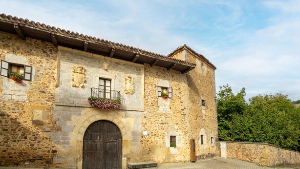 A stone building with a large arched entrance, multiple windows, and a tiled roof. - Tranquil Stay Near Luna River (Benllera, Carrocera, León)