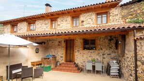 A stone building with a tiled roof, a wooden porch, and outdoor seating. - Tranquil Stay Near Luna River (Benllera, Carrocera, León)