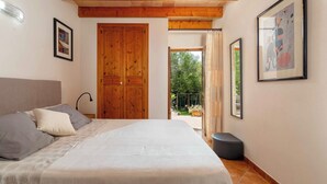 A bedroom with a bed, a wooden door, a balcony, and a framed picture on the wall.