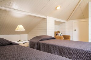 A bedroom with two beds, a nightstand with a lamp, a chair, and a door. - HOME ARAÚJO - (13090 / AL) fantastic view of the village and the beach of Ponta do Sol (Ponta do Sol)