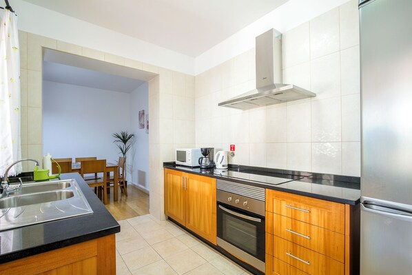 A modern kitchen with wooden cabinets, a stainless steel refrigerator, a microwave, and a coffee maker. - HOME ARAÚJO - (13090 / AL) fantastic view of the village and the beach of Ponta do Sol (Ponta do Sol)