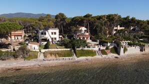 A coastal residential area with houses, a clear beach, and a mountainous background. - Seafront house with private access to the sea. Completely renovated in 2016 (Pula)