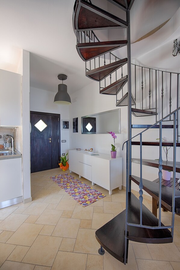 Et moderne interiør med en spiraltrappe, et køkkenområde og en opholdsstue med sofa og sofabord.