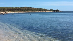 A clear coastal view with a sandy beach, calm sea, and a forested hill in the background. - Seafront house with private access to the sea. Completely renovated in 2016 (Pula)
